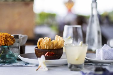 Nacho maxican cipsleri, Endonezya, Bali 'de doğaya yakın bir restoranda öğle yemeği sırasında, hoş geldin içkisi ve biber sosuyla birlikte ahşap bir kasede servis edilir.