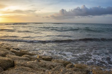 Endonezya 'nın Bali şehrinde yaz mevsiminde ufuk çizgisi olan deniz kenarındaki bulutların üzerinde gün batımından doğan güneş ışığı
