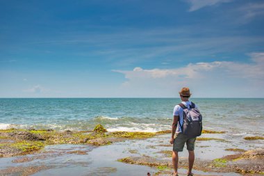 Gökyüzünde bulutlar ve Endonezya 'nın Bali kentindeki bir turistin tadını çıkardığı yeşil sularla dolu sakin bir deniz manzarası.