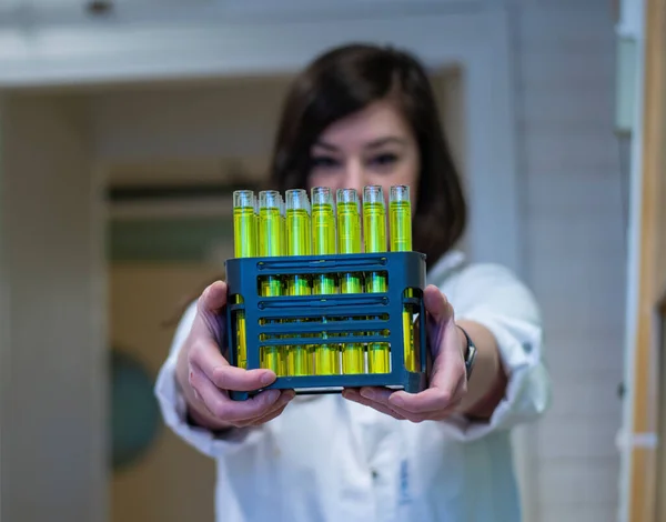 A woman chemist holding fractions of compound collected from column chromatography in a chemistry laboratory for biomediacal research