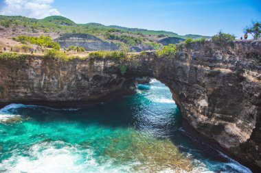 Yazın Nusa Penida, Bali 'ye yapılan turistik ziyaret sırasında tepeden gelen kırık sahil kıyısı yeşil-su dalgası.