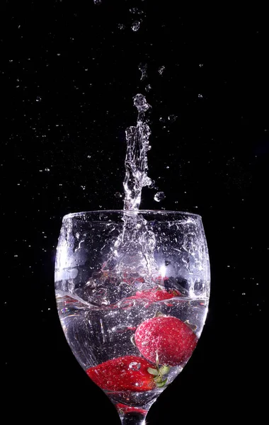 Ein Paar Erdbeeren Die Auf Ein Glas Voll Schnaps Fallen lizenzfreie Stockfotos