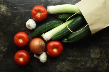 Masaya bırakılan bir kese kağıdı ve sebze dökülmüş.