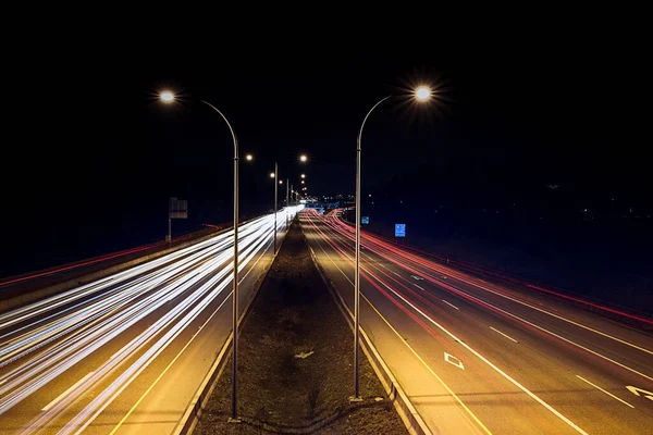 Speed traffic - light trails on highway at night. Cars exiting highway