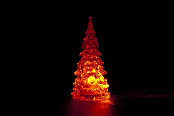 Glass Christmas tree with red led isolated on black background. Horizontal shot.