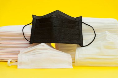 Virüslere, gribe ve diğer hastalıklara karşı korumak için çeşitli renklerde cerrahi maskeler. Sarı arka planda izole edilmiş. Yakın plan. Yatay çekim.