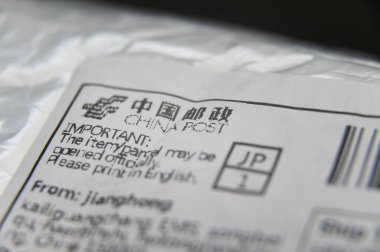 Fuji City, Shizuoka Prefecture, Japan - March 22, 2020: Bubble wrap padded envelope with close- up on China Post label. Isolated on black background. clipart