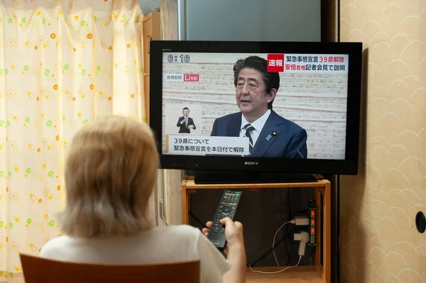 Fuji Şehri, Shizuoka, Japonya - 14 Mayıs 2020: Coronavirus (COVID-19) salgını. Bir kadın Japon televizyonunda Başbakan Shinzo Abe 'in 39 vilayetteki 