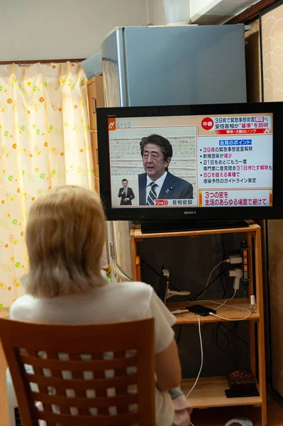 Fuji Şehri, Shizuoka, Japonya - 14 Mayıs 2020: Coronavirus (COVID-19) salgını. Bir kadın Japon televizyonunda Başbakan Shinzo Abe 'in 39 vilayetteki 