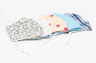 Koronavirüs (COVID-19) ve diğer bulaşıcı hastalıklara karşı korunmak için renkli ve çiçek desenli DIY yüz maskeleri. Beyaz arka planda izole edilmiş. Uzayı kopyala Yatay çekim.