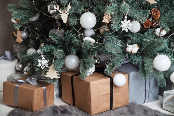 Dárkové krabice zabalené v papíru Kraft leží pod vánočním stromečkem. — Stock fotografie