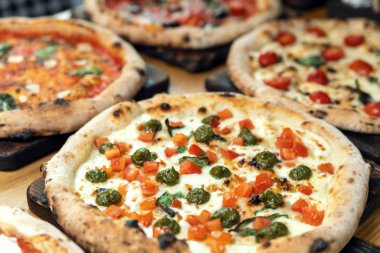 Bir İtalyan restoranında ahşap bir masada bir sürü yeni hazırlanmış pizza.