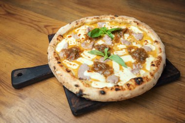 Peynirli, soslu, sebzeli ve ahşap bir masada taze pişmiş pizza.. 