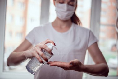 Kız ellerini dezenfektanla tedavi ediyor.