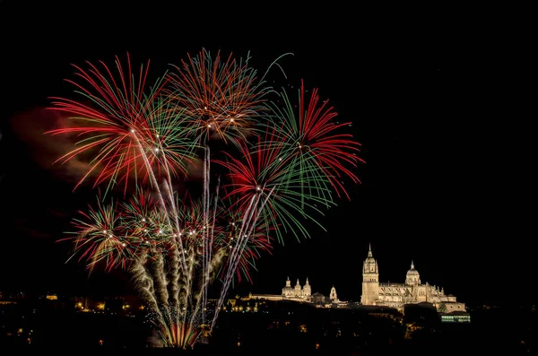 Illuminated cityscape of the city of Salamanca and fireworks against the sky at night