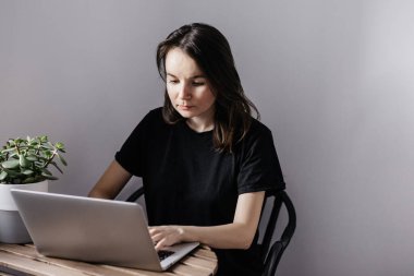 Genç bayan evde dizüstü bilgisayarla çalışıyor. 