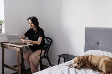 Genç bayan evde dizüstü bilgisayarla çalışıyor. 