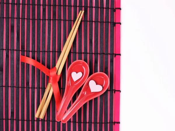 Alla hjärtans dag, kvinnor, mödrar dag koncept.Set sushi och ätpinnar bundna byråkrati på trä bakgrund.Red sushi rätter med rosa små hjärtan på svart och röd asiatisk matta. Ovanifrån, kopiera utrymme. — Stockfoto