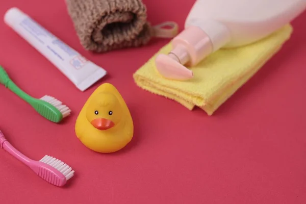 Spa ve banyo konsepti. Bebek banyosu. Parlak pembe arka planda şirin bir çocuk spa kompozisyonu. Sabun şişesi, havlu, bez, plastik ördek oyuncağı ve diş fırçası. Uzayı metin için kopyala. Seçici odak.