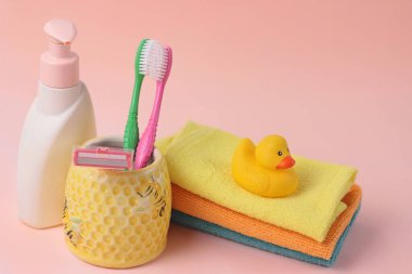 Spa ve banyo konsepti. Bebek banyosu seti. Pembe arka planda parlak renklerde şirin çocuk spa kompozisyonu ve fotokopi alanı. Sabun şişesi, renkli havlular, plastik ördek oyuncağı ve diş fırçaları..