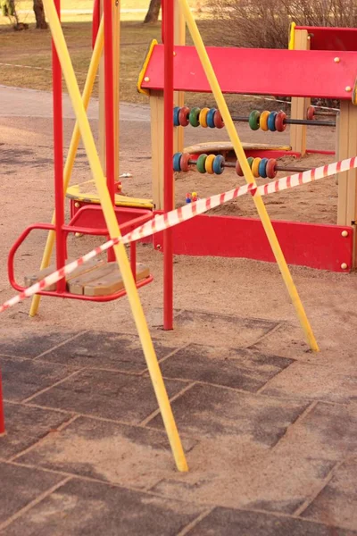Modern playground closed for coronavirus quarantine. Colorful bright children playground with bounding tape in public park. Modern playground with rubberized coating