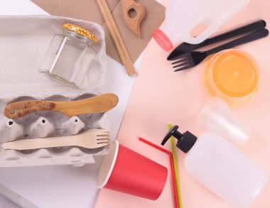 Anneler Günü konsepti. Çevre dostu, tek kullanımlık, geri dönüşümlü, gübrelenebilir sofra takımı ve ambalaj. Plastik ve kağıt bardaklar, çanaklar, tabak, paket beyaz ve pembe arka plan. üst görünüm