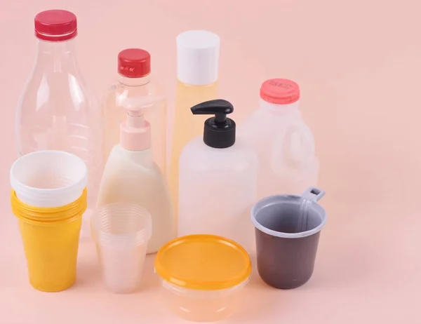 Toprak Ana Günü. Plastik ambalaj konsepti. Pembe arka planda boş şeffaf plastik şişeler ve bardaklardan oluşan bir grup. Kopya alanı ile ön görüş