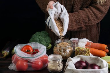 Yeniden kullanılabilir cam bankayı geri dönüşüm çantasından çıkan ürünlerle dolduran kadın