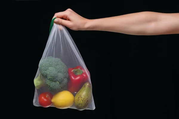 Mano sosteniendo blanco reutilizable bolsa llena de verduras frescas —  Fotos de Stock