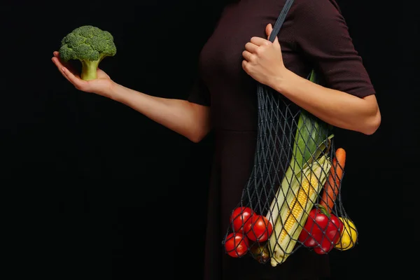 Female holding reusable string bag full of fresh vegetables over