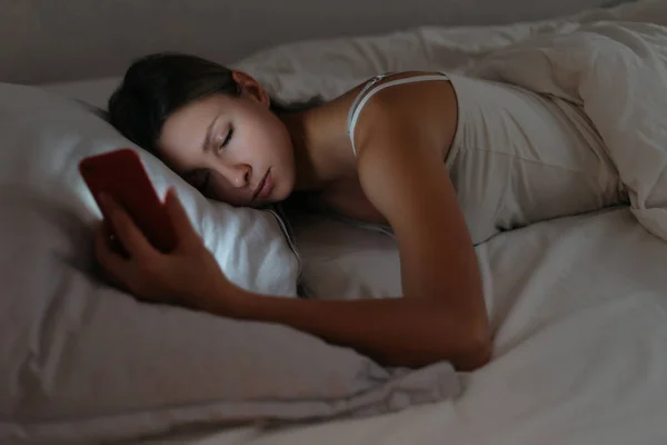 Jonge vrouw viel in slaap tijdens het gebruik van smartphone 's nachts. — Stockfoto