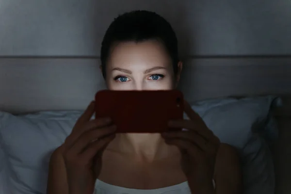 Jong vrouw met behulp van haar smartphone laat in de nacht in haar bed voor w — Stockfoto