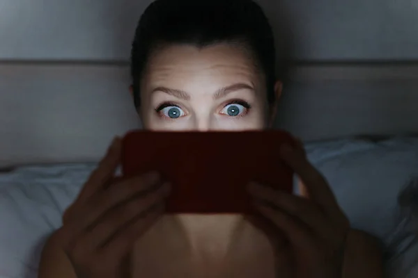 Meisje verslaafd staren naar haar smartphone laat in de nacht in bed. — Stockfoto