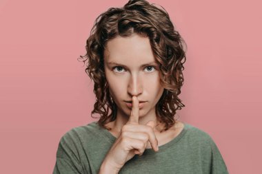 Kıvırcık beyaz genç kadın ciddi görünüyor, ona parmak tutarak