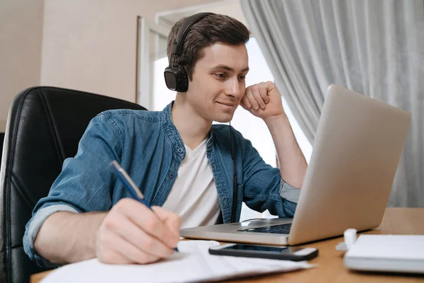 Uzaktan eğitim için dizüstü bilgisayar kullanan mutlu çocuk öğrenci, konferans videosundan zevk alıyor, webinar izliyor, ses dersleri dinliyor, notlar yazıyor, öğretmenle çalışıyor, ders alıyor.