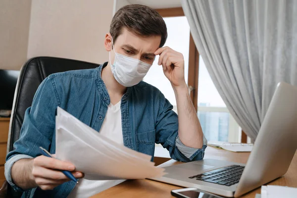 Korunaklı maskeli genç adam Coronavirus ya da COVID-19 karantinası sayesinde çalışıyor ve uzaktan çalışıyor. Çevrimiçi eğitim ve evden dizüstü bilgisayarla serbest çalışma. Okulları kapatmak, işini kaybetmek.