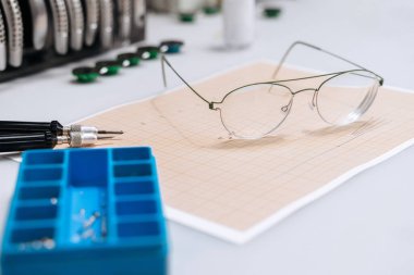 Masanın üzerinde farklı renkte ve biçimlerde birçok tapınak bulunan gözlüklerin yakın çekimi. Profesyonel gözlük üretimi ve onarımı. Gözlük ölçme ve hazırlama uzmanı.