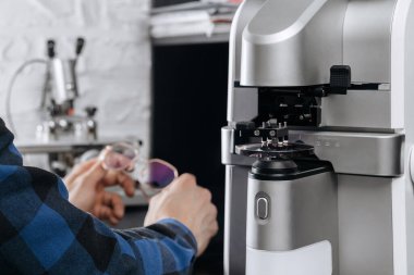 Optisyen atölyesinde gözlük tutan genç bir optometrist. Gözlükçünün ofisinde özel aletleri ve ekipmanı olan gözlük merceği üretimi
