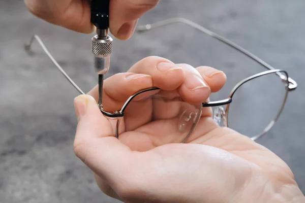 Gözlükçü ustanın optikte özel profesyonel aletler kullanarak yeni gözlük yaptığı yakın plan. Kırık bardak konseptini tamir etmek