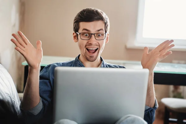 Happy surprised man with laptop at home, got pleasant email, good news, won the lottery, found new job, successfully passed exam. Exited businessman looking at his computer. Remote work concept