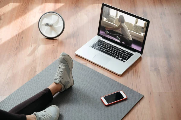 İnternette yoga derslerini izlemek için dizüstü bilgisayar kullanan sağlıklı genç bir kadının yakın çekimi. Evde online antrenman. Salgın sırasında ev sağlığı, karantina ve kendini izolasyon