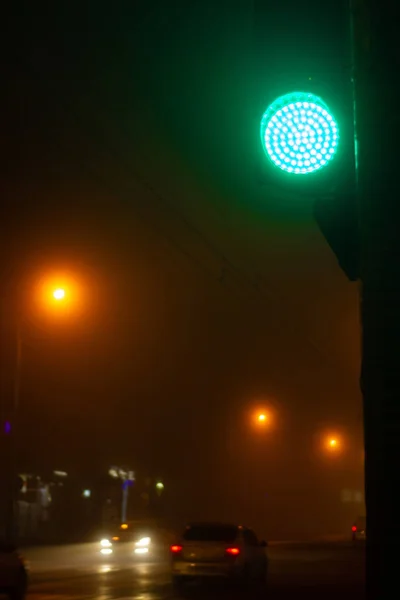 Зеленый сигнал светофора и размытая езда в темную туманную ночь — стоковое фото
