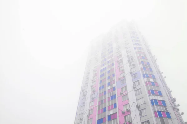 Renkli paneli olan yüksek apartman blokları sisli gökyüzünde kayboluyor ve metin için kopyalama alanı var — Stok fotoğraf