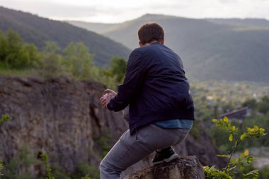 Kamp turizmi sırasında dağlardan aşağıya bakan bir adamın arka görüntüsü.