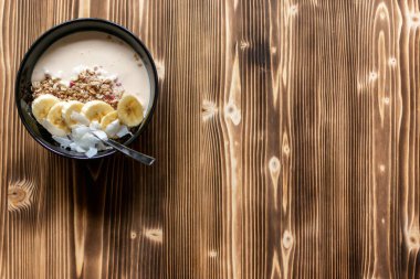 Sağlıklı kahvaltı için koyu ahşap zemin üzerinde bir kase granola ve metin için kopya alanı.