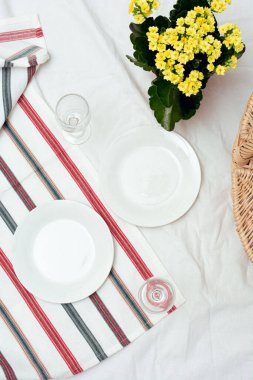 Hasır sepetli, tabaklı, beyaz battaniyeli iki kişilik piknik. Açık hava romantik piknik buluşması konsepti