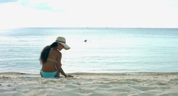 Mujer sentada en la playa y jugando — Vídeo de stock
