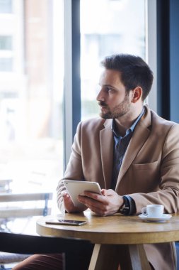 Kafede oturan ve pencereden dışarı bakarak adam