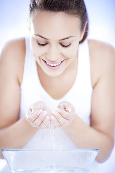 Ung kvinna tvätta hennes ansikte — Stockfoto
