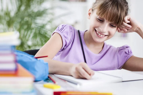 Gülümseyen kız ödevini evde yapıyor — Stok fotoğraf
